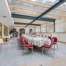 Elegant conservatory with table setting and red chairs.