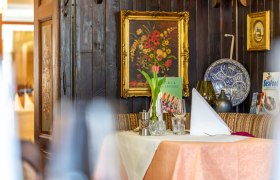 A cozy table setting in a rustic restaurant with a flower picture and decorations on the wall.