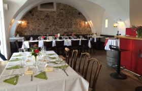 Cozy dining room with covered tables, stone wall and vaulted ceiling.