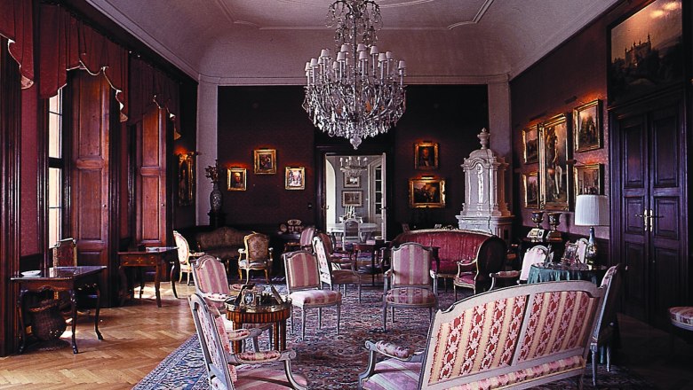 Elegant salon with antique furniture, chandelier and paintings.