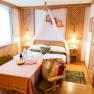 Cozy double room with wooden furniture, a table with drinks and snacks, and a bed with canopy.