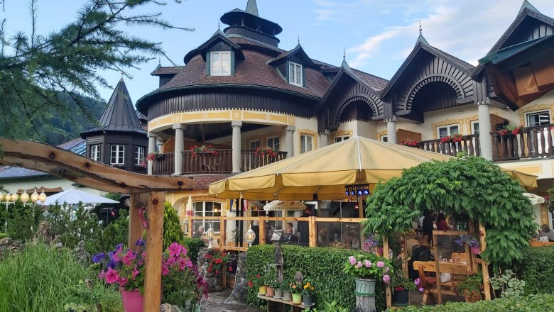 A traditional building with wooden balconies and a yellow parasol in the garden.