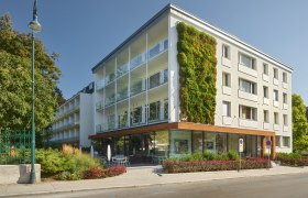 Modern building exterior with vertical garden and glass balconies in daylight.