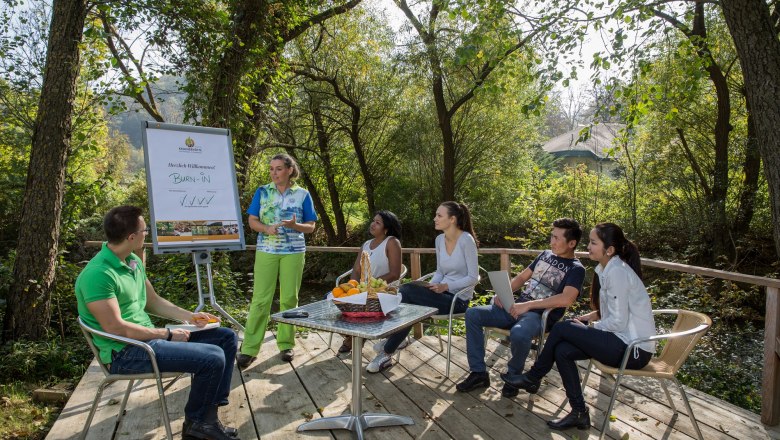 Group of people at an outdoor meeting in a wooded area.