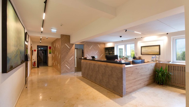 A hotel reception area featuring a modern design, wooden elements, and a large reception desk.