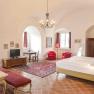 Luxurious suite with antique furniture, red carpets and curtains, a large bed and a chandelier.