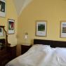 Bedroom with double bed, yellow walls and several framed pictures on the wall.