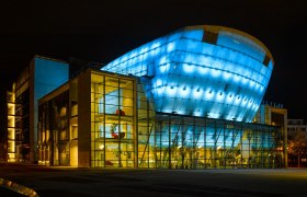 Festspielhaus St. Pölten at night, illuminated in blue and yellow.