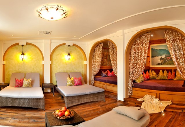 A cozy wellness room with loungers, curtains and cushions.