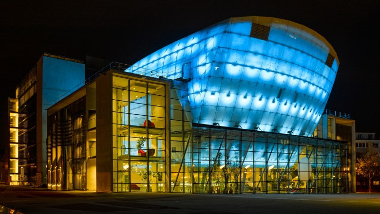 St. Pölten Festival Hall at night, illuminated in blue and yellow.