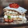 A cream slice with puff pastry, cream and strawberries on a plate.