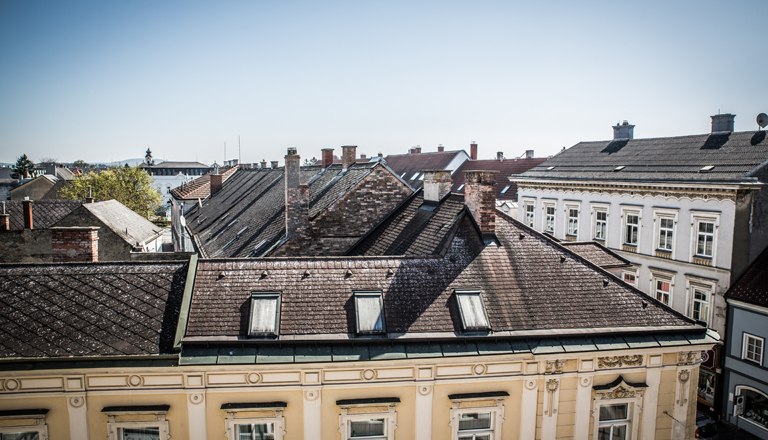 View of the roofs of the neighboring buildings and blue sky.