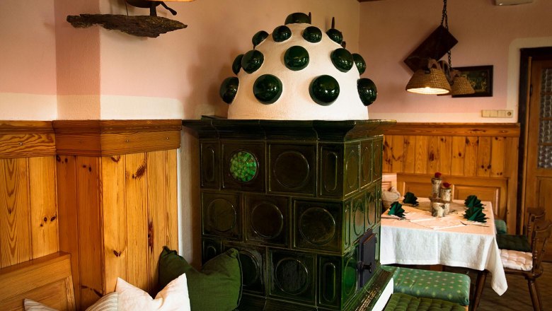 Cozy, traditional parlor with green tiled stove and wooden furniture.