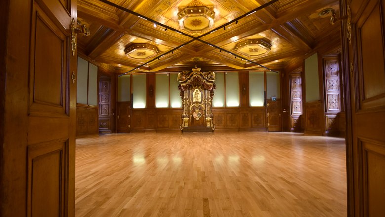 Interior view of the Knights' Hall in Palais Niederösterreich with wooden floor and ornate wooden ceiling.