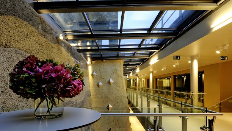 Modern vestibule of BURG Perchtoldsdorf with glass roof and flower arrangement.