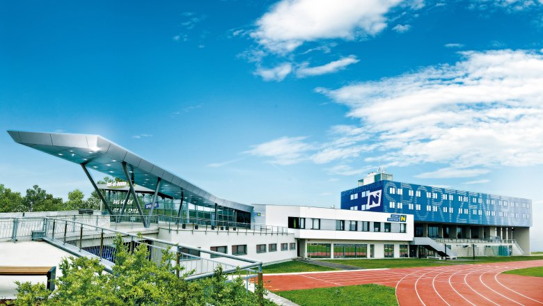 Modern sports center with running track and blue sky.