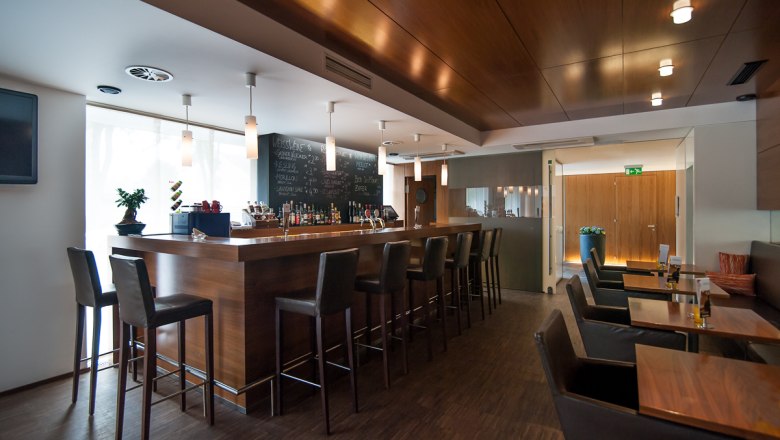 Modern bar with wooden counter and high stools.