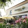 Exterior view of the Donaulodge with terrace, parasols and flowering plants.
