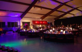 Interior view of a festively lit hall with laid tables and guests.