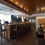 Modern bar with wooden counter and high stools.