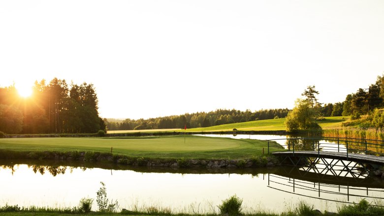 Golf course with pond and bridge at sunset at the Haugschlag golf resort.