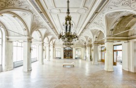 Large, elegant dining room with ornate ceilings and chandeliers in the Südbahnhotel.