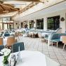 A bright conservatory with laid tables and wooden furniture.
