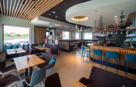 Modern bistro with wooden furniture, bar and large windows.