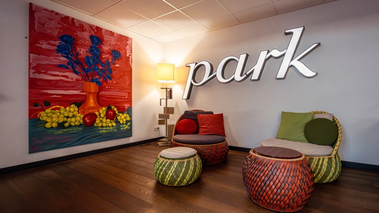 A stylish hotel lounge area with colorful furniture and a large painting on the wall.
