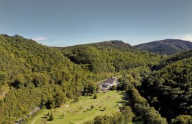 Aerial view of the Krainerhütte amidst wooded hills.