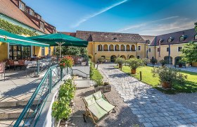 Inner courtyard of the Althof Retz with terrace, parasols and garden.