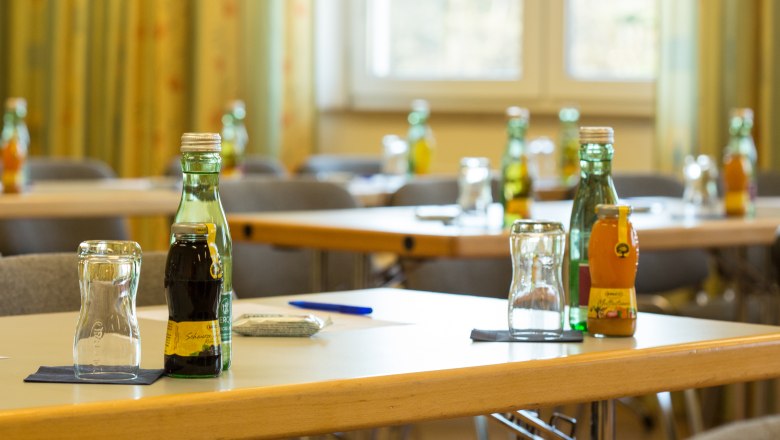 A seminar room with tables on which drinks and glasses are placed.