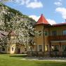 A yellow hotel with red roofs and a blossoming tree in the foreground.