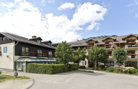 A traditional inn surrounded by trees, with mountains in the background.