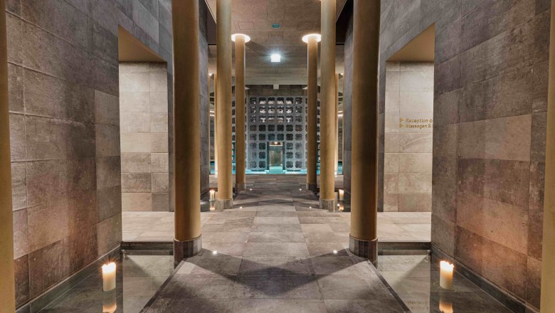 Interior view of a modern spa with high columns and candlelight.