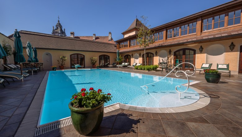 Outdoor pool at Hotel Schloss D&uuml;rnstein with sun loungers and parasols.