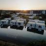 Aerial view of modern buildings on the waterfront at the Laa thermal spa resort at sunset.