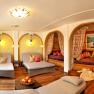 A cozy wellness room with loungers, curtains and cushions.