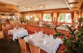 Elegant restaurant with laid tables and red upholstered furniture.