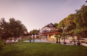 Large house with garden and pool at sunset.