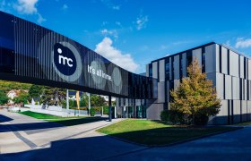 Modern IMC Krems building with glass bridge and 'It's all in me' lettering.