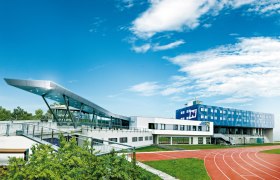 Modern sports center with running track and blue sky.