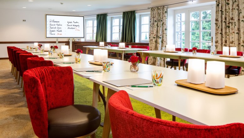 Elegant seminar room with red chairs and white tables.