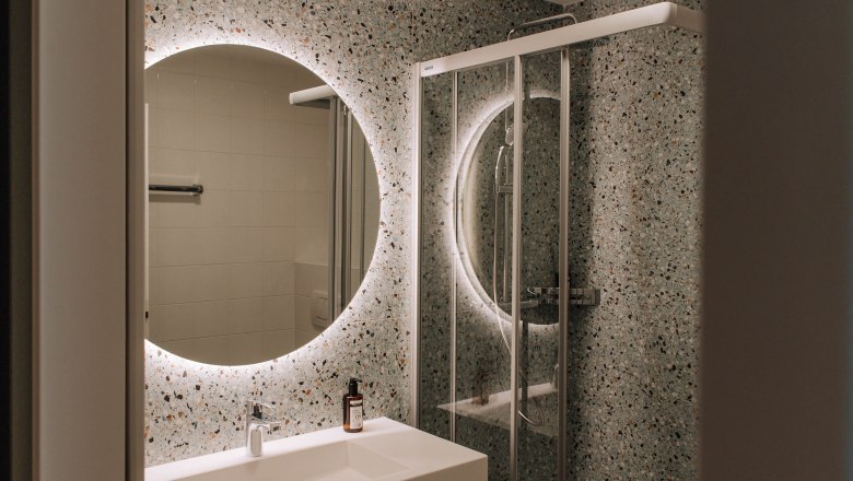 Modern bathroom with illuminated mirror and shower.