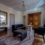 Elegant living room with antique wardrobe, large mirror, black leather furniture and a chandelier.