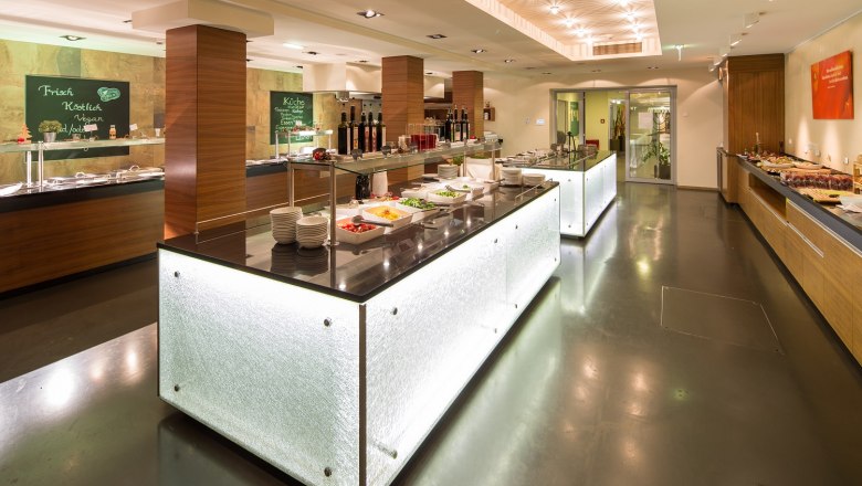 Modern buffet in a hotel restaurant with illuminated counters and various dishes.