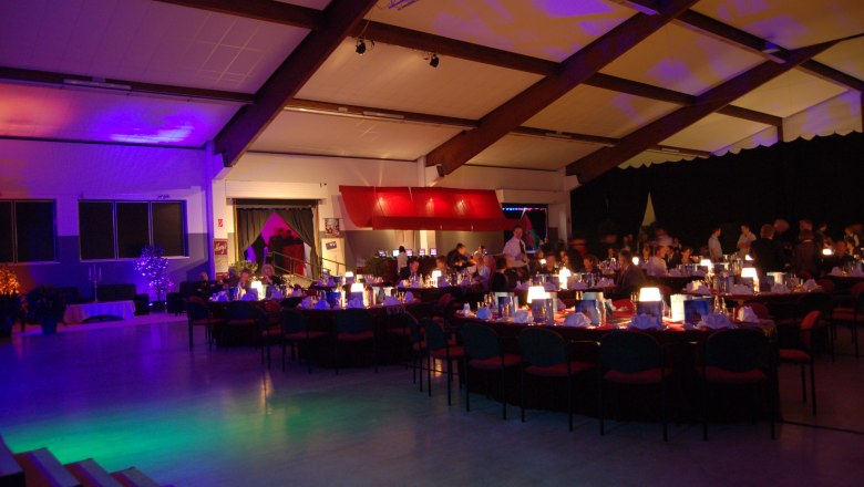 Interior view of a festively lit hall with laid tables and guests.