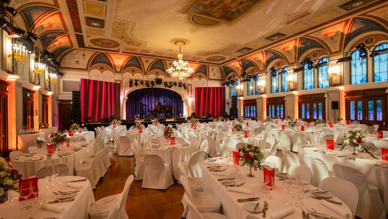 Elegant ballroom with set tables and stage at the Congress Center Baden.