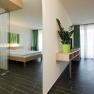 Modern hotel room with double bed, green curtain and houseplant.