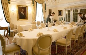 Elegant dining room with laid table, candlesticks and two waiters.